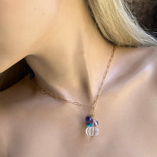 Load image into Gallery viewer, A close-up of a model's neck and collarbone wearing a delicate gold chain necklace with a pendant featuring purple and blue marbled beads and a clear faceted crystal.