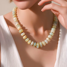 Load image into Gallery viewer, Necklace with light-colored beads being worn by a person in a white outfit.
